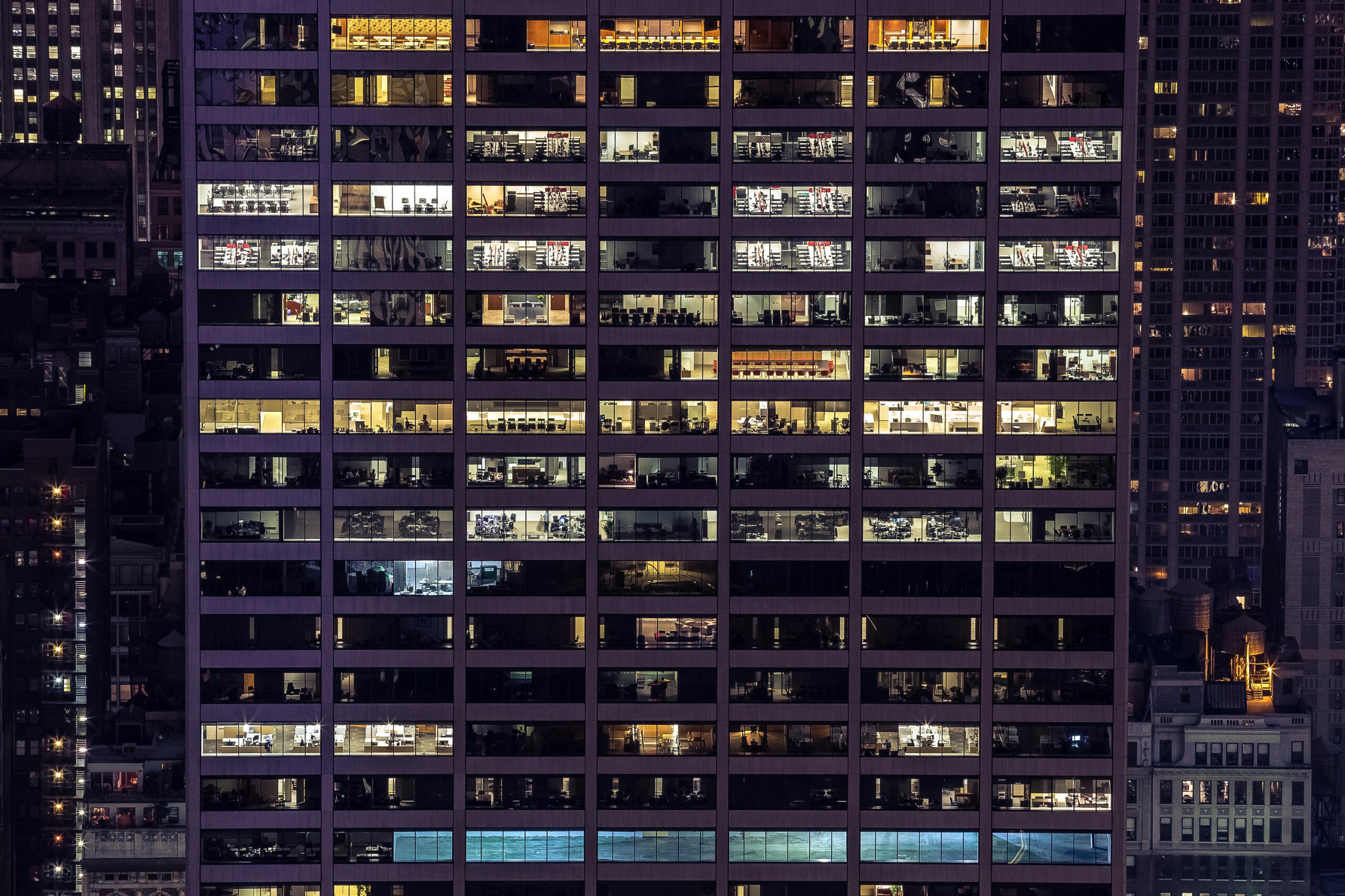 Many windows of an office building, some of which are lit up.